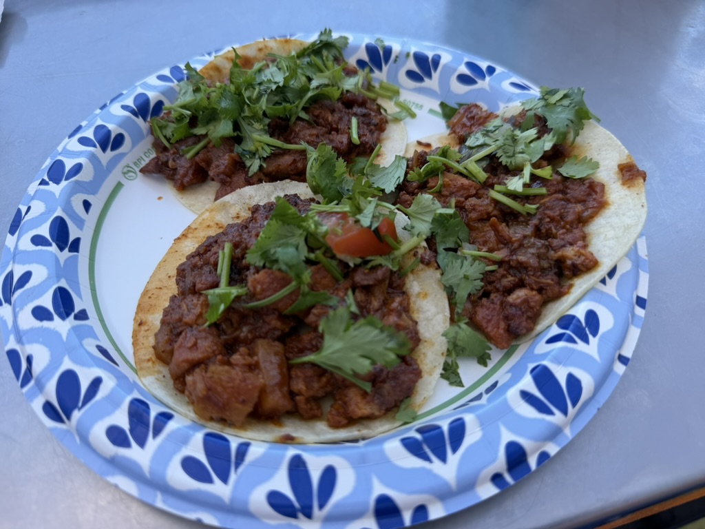 Tres tacos de Antojitos Corona en un plato, con carne, cilantro y salsa