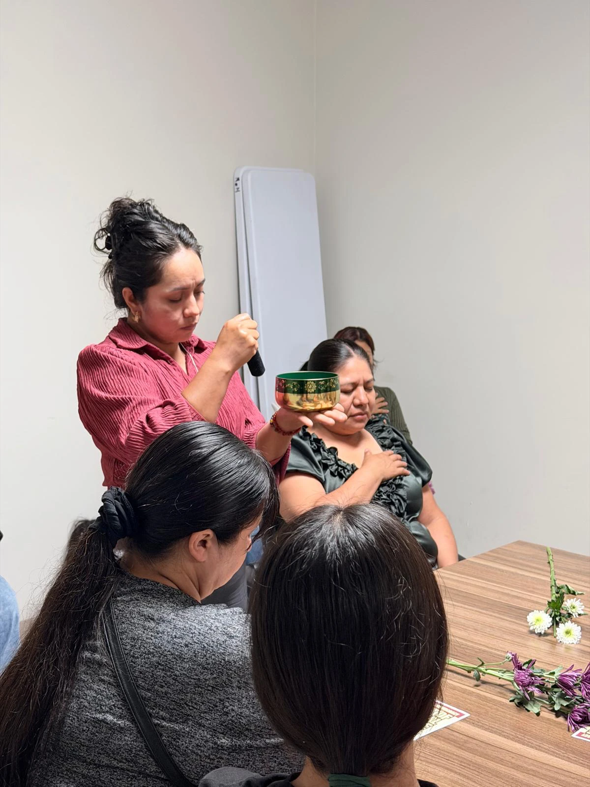 Ana Lilia Morales sostiene un cuenco tibetano sobre una clienta durante una sesión de terapia de sonido